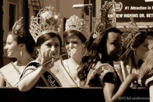 Pageant queens on a parade float waving.
