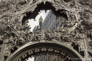 Ornate metalwork with city reflection in window.