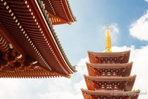 Japanese temple roof and pagoda against sky.