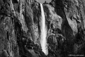 Waterfall cascading down rocky cliff face.