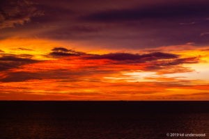 Vibrant orange and purple sunset over ocean.