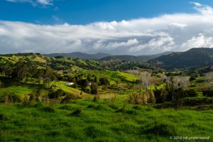 Green hills under a cloudy blue sky.