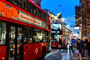 Red buses on busy festive street.