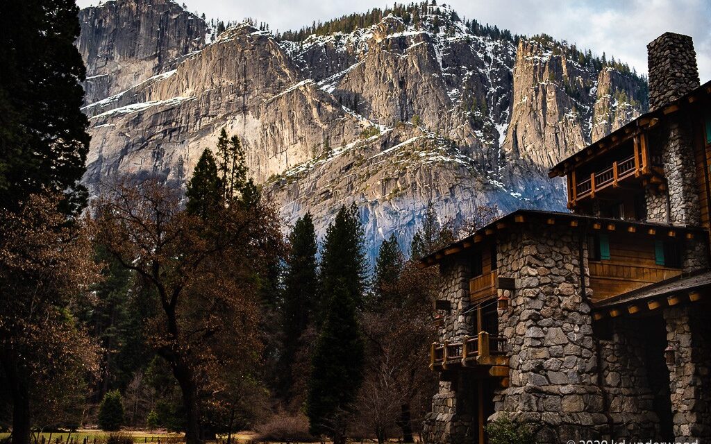 Mountain lodge with rocky cliff backdrop.