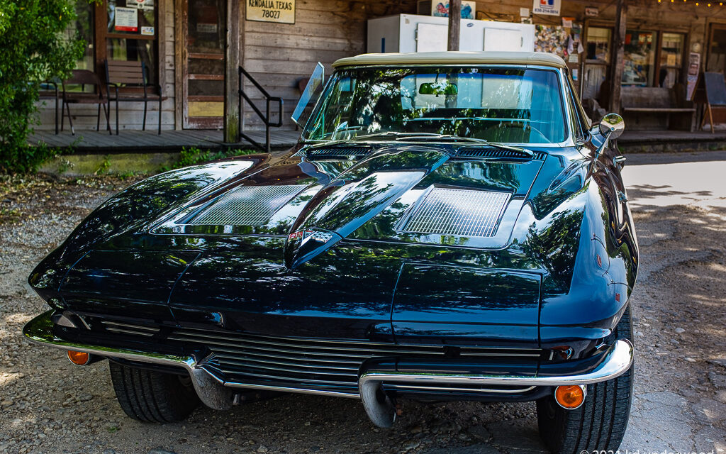 Classic black sports car parked outside building.
