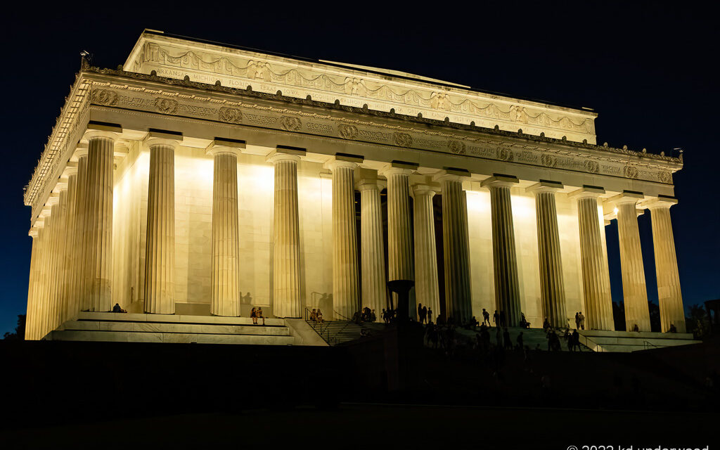 Illuminated building with columns at night.
