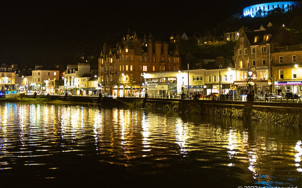 Nighttime waterfront cityscape with illuminated buildings.